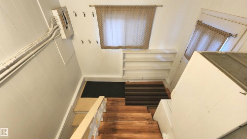 Wood-finish stairs leading to a landing with built-in shelving and two windows - 9359 92 Street, Edmonton, AB 
