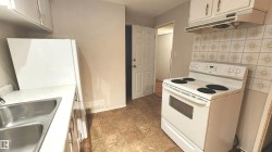 Kitchen featuring tiled flooring, white cabinetry, a double basin stainless steel sink, and a patterned tile backsplash - 
