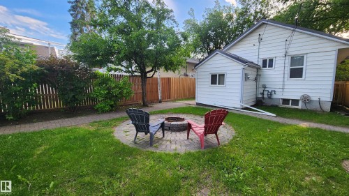 Manicured lawn featuring a circular paver patio with a built-in fire pit - 9359 92 Street, Edmonton, AB 