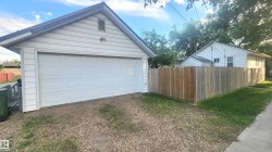 Detached garage with panel-style door, gravel driveway, and wood privacy fencing - 