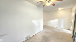 Spacious interior room featuring light-colored walls, ceiling fan with integrated lighting, and wall-mounted light fixtures - 
