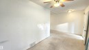 Spacious interior room featuring light-colored walls, ceiling fan with integrated lighting, and wall-mounted light fixtures - 9359 92 Street, Edmonton, AB 