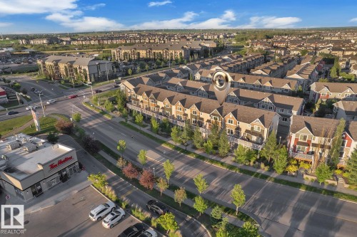 Aerial perspective showcasing a row of multi-story townhomes with varied exterior finishes and private balconies - 140 655 Tamarack Road, Edmonton, AB 
