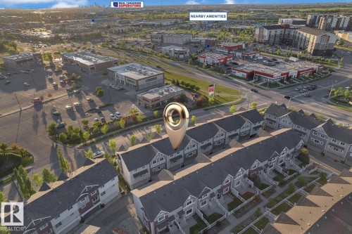 Aerial perspective showcasing a row of townhomes with dark shingle roofs and light-colored siding - 140 655 Tamarack Road, Edmonton, AB 