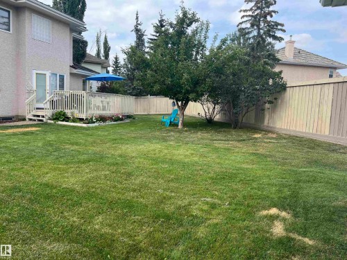 Expansive backyard featuring a large grass lawn, mature trees, a multi-level deck with white railings, and a privacy fence - 1417 115A Street, Edmonton, AB - Outdoor