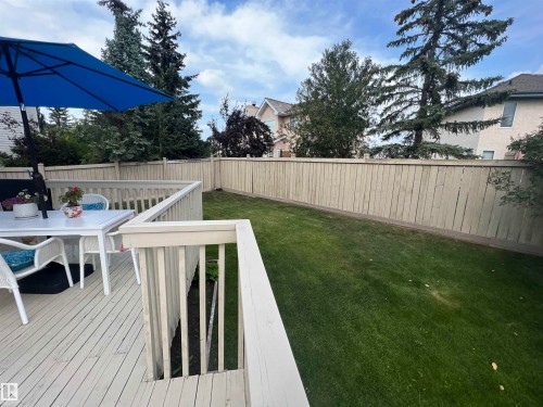 Spacious backyard featuring a wooden deck with railing, a manicured lawn, and a tall privacy fence - 1417 115A Street, Edmonton, AB - Outdoor