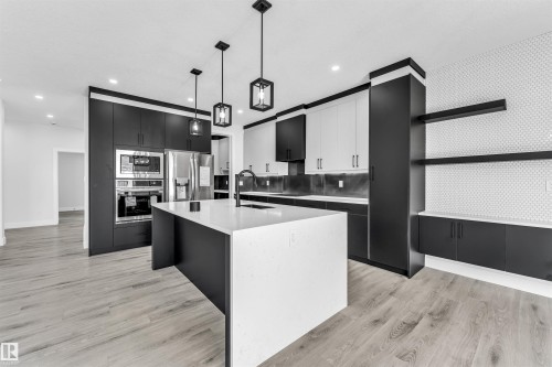 Contemporary kitchen featuring a white quartz island with an undermount sink and matte black faucet - 11 Southbridge Crt, Calmar, AB 