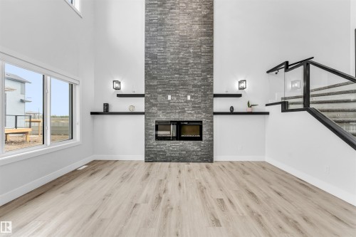 Living area featuring a floor-to-ceiling slate-style fireplace, integrated electric fireplace, and light wood-finish flooring - 11 Southbridge Crt, Calmar, AB 