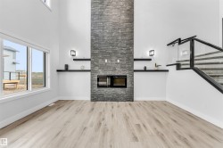 Living area featuring a floor-to-ceiling slate-style fireplace, integrated electric fireplace, and light wood-finish flooring - 