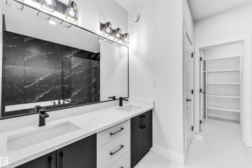 Dual vanity featuring integrated sinks, white countertops, and black cabinetry with matte black hardware - 11 Southbridge Crt, Calmar, AB 