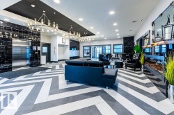 Lobby featuring black and white chevron pattern flooring, polished black marble-look wall tiling, recessed lighting, and multiple contemporary chandeliers - 