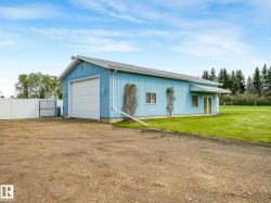 Light blue corrugated metal building featuring a large white garage door, two rectangular windows, and a sliding glass entry door - 