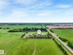 Expansive rural property featuring an established treeline, cultivated fields, and a paved road frontage - 