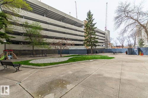 Paved outdoor courtyard featuring a central landscaped area with grass and decorative rocks - 8510 111 Street, Edmonton, AB 