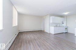 Spacious living area featuring wood-finish flooring, white walls, and vertical blinds - 