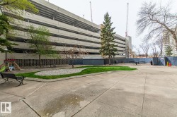 Paved outdoor courtyard featuring a central landscaped area with grass and decorative rocks - 