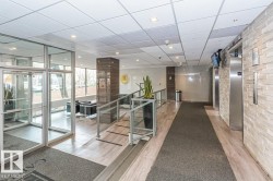 Building lobby featuring glass entry doors, wood-finish flooring, and a textured stone wall - 