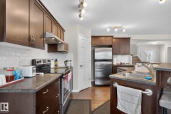 Kitchen featuring dark wood cabinetry, white subway tile backsplash, stainless steel appliances, a double basin sink, and laminate countertops - 