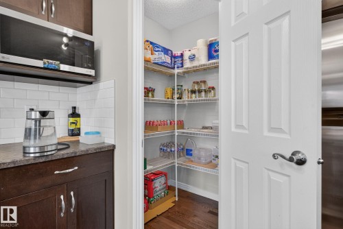 Corner pantry with multiple wire shelves, wood-finish flooring, and a paneled door - 7858 170A Avenue, Edmonton, AB 