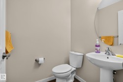 Powder room featuring a pedestal sink with chrome faucet, a standard toilet, and wood-finish flooring - 