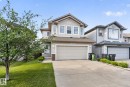 Two-story residential exterior featuring light-colored siding, a two-car attached garage, stone accents, and a concrete driveway - 7858 170A Avenue, Edmonton, AB 