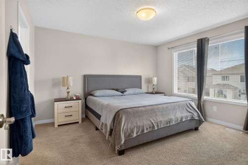 Carpeted bedroom featuring light neutral wall paint, white trim, and a ceiling-mounted light fixture - 7858 170A Avenue, Edmonton, AB 