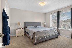 Carpeted bedroom featuring light neutral wall paint, white trim, and a ceiling-mounted light fixture - 