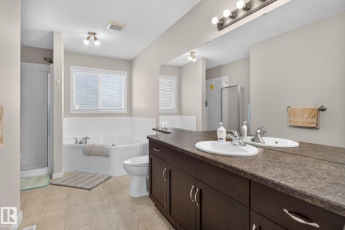 Expansive bathroom featuring a dual vanity with integrated sinks, a wide mirror, and a full-size bathtub - 7858 170A Avenue, Edmonton, AB 