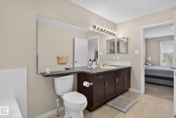 Bathroom featuring a dark wood-finish vanity with an integrated sink and ample storage - 