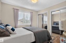 Bedroom featuring a window with horizontal blinds and curtains, two mirrored sliding closet doors, a flush-mount ceiling light, and neutral wall paint - 