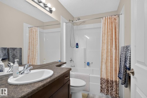 Bathroom featuring a dark wood vanity with an integrated oval sink, a speckled countertop, and a vanity mirror - 7858 170A Avenue, Edmonton, AB 