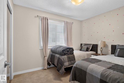Carpeted room with a textured ceiling and a window featuring blinds and drapes - 7858 170A Avenue, Edmonton, AB 