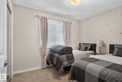 Carpeted room with a textured ceiling and a window featuring blinds and drapes - 