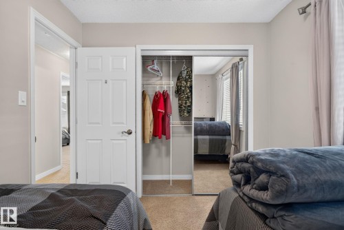 Bedroom featuring carpeting, a white panel door, and mirrored closet doors with wire shelving - 7858 170A Avenue, Edmonton, AB 