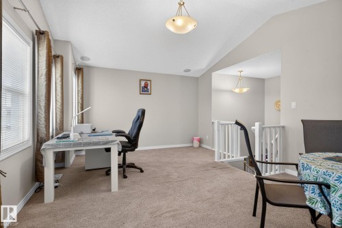 Carpeted upper-level space featuring a white painted railing, multiple windows with blinds, and ceiling-mounted light fixtures - 7858 170A Avenue, Edmonton, AB 
