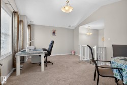 Carpeted upper-level space featuring a white painted railing, multiple windows with blinds, and ceiling-mounted light fixtures - 