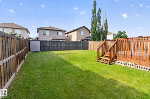 Spacious fenced backyard featuring a wood deck with stairs, a green lawn, and a storage shed - 7858 170A Avenue, Edmonton, AB 