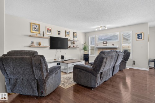 Hardwood-finish flooring throughout the main living area, featuring light-toned wall paint and white trim - 7858 170A Avenue, Edmonton, AB 