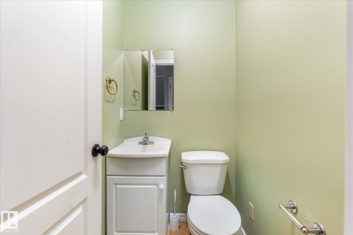 Bathroom featuring a white toilet, single vanity with integrated sink, chrome faucet, and a wall-mounted mirror - Fort Saskatchewan, AB 