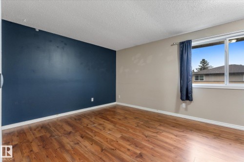 Spacious room with wood-finish flooring, a feature wall, and a large window - Fort Saskatchewan, AB 
