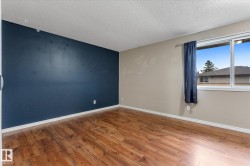 Spacious room with wood-finish flooring, a feature wall, and a large window - 