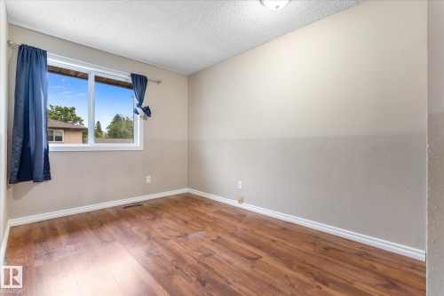 Room featuring wood-finish flooring, white baseboards, and a single window with white trim - Fort Saskatchewan, AB 