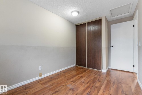 Room featuring wood-finish flooring, a ceiling-mounted light fixture, and a built-in closet with sliding wood-panel doors - Fort Saskatchewan, AB 