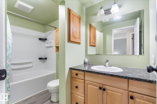 Bathroom featuring a vanity with a white oval sink, dark countertop, and wood-finish cabinetry - Fort Saskatchewan, AB 