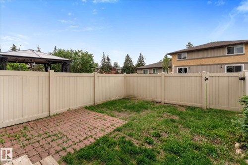 Enclosed backyard featuring a tan privacy fence, a brick paver patio, and green space - Fort Saskatchewan, AB 