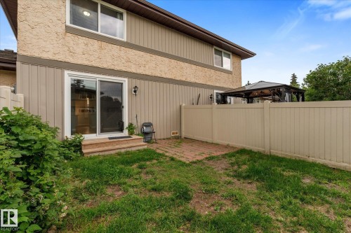 Rear exterior featuring a sliding glass patio door, a tan privacy fence, and a brick paver patio area - Fort Saskatchewan, AB 
