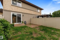 Rear exterior featuring a sliding glass patio door, a tan privacy fence, and a brick paver patio area - 