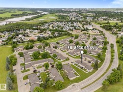 Aerial overview of a residential complex featuring multiple attached homes with light-colored siding and dark roofs - 