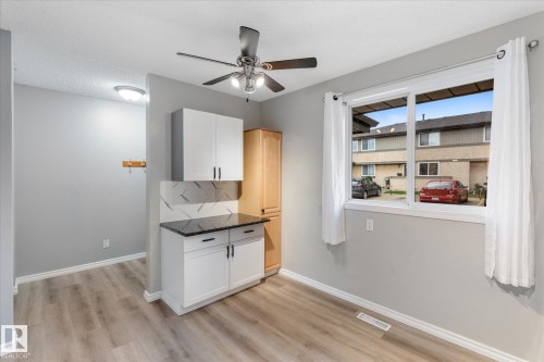 Light-filled room featuring wood-finish flooring, a ceiling fan with integrated lighting, and a window with white trim - Fort Saskatchewan, AB 