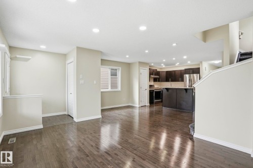 Open-concept living area featuring rich wood-finish flooring and recessed lighting - 445 Watt Boulevard, Edmonton, AB 